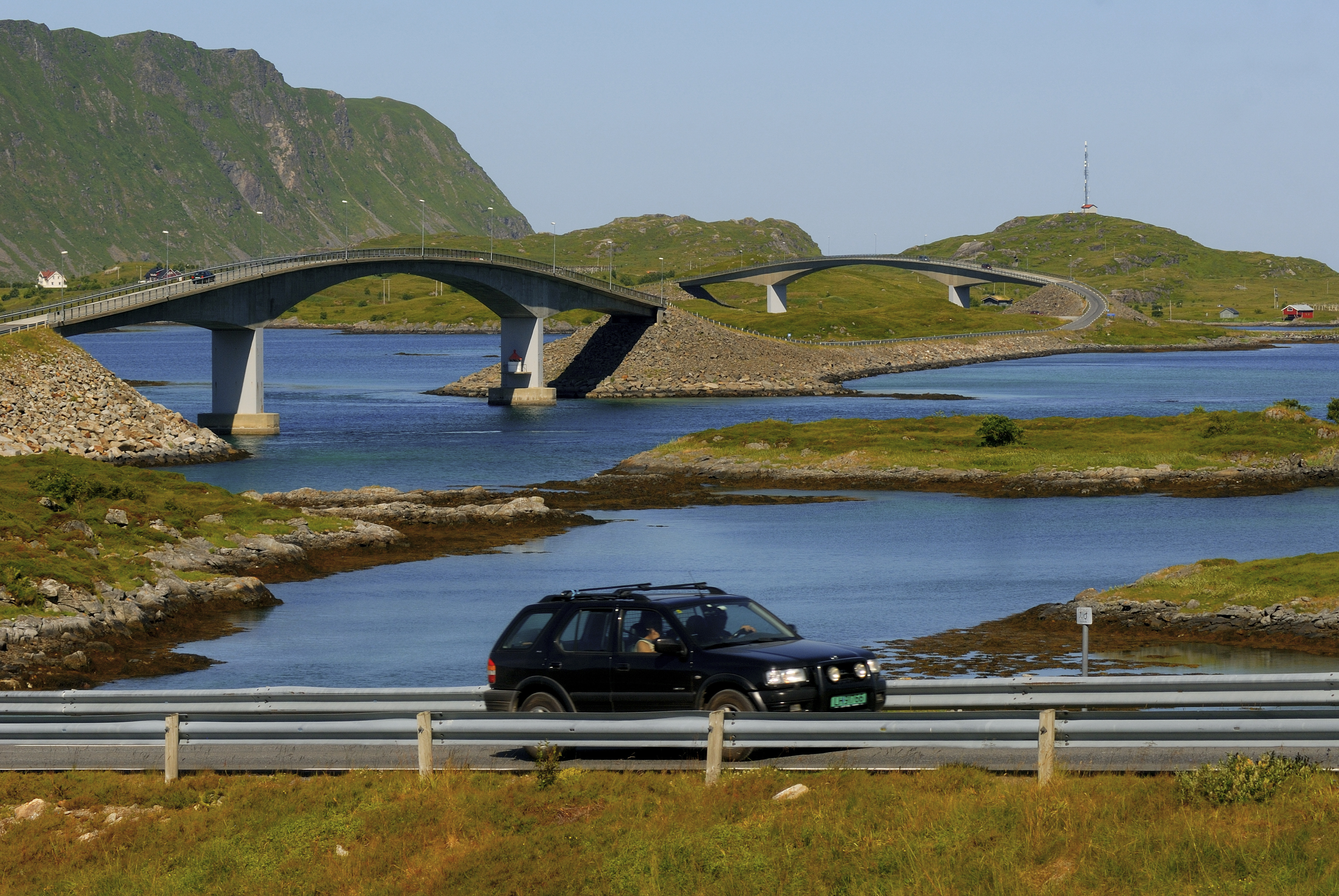 En bil kjører i øde landskap i Lofoten