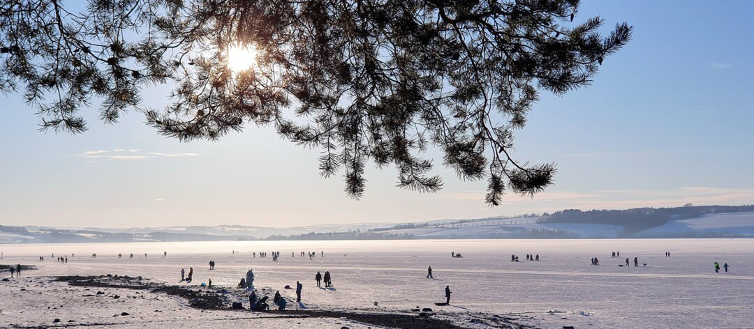 Bilde av en islagt sjø med mennesker som går på isen.